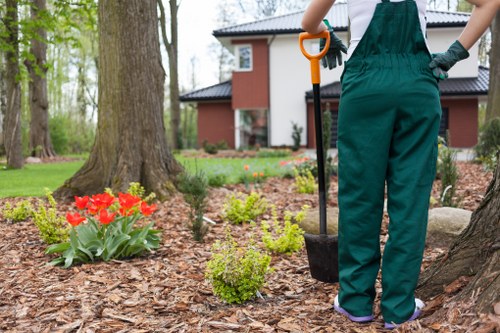 Operative using a maintained powered hedge trimmer with PPE